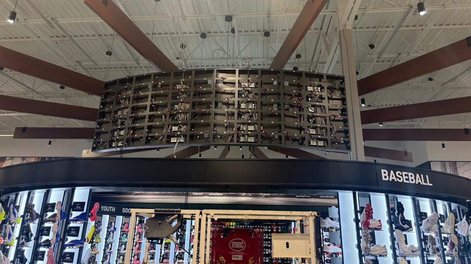 Before: the back of the curved LED video wall at Dick's Sporting Goods during the install, with bare panel frames, exposed wiring, and a lift below.
